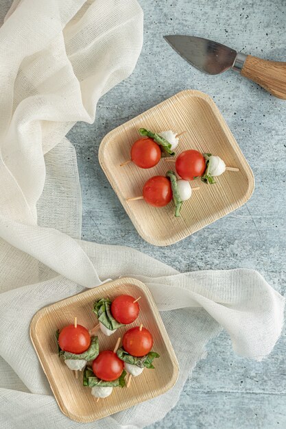 Round red fruits on sticks on rounded-square brown platters