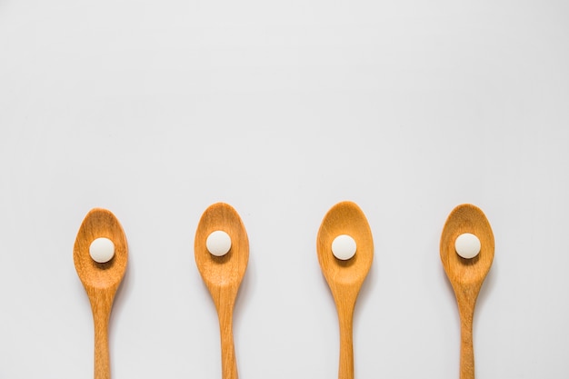 Round white pill on wooden spoons over the white background