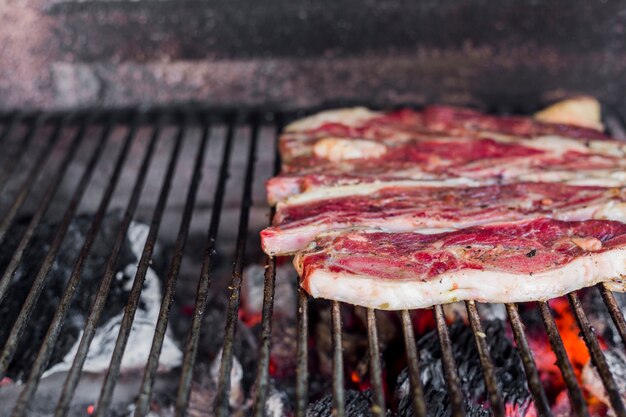 Row of beef fillet being cooked over coals in barbecue