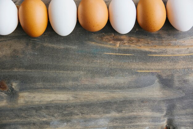 Row of brown and white eggs on wooden background