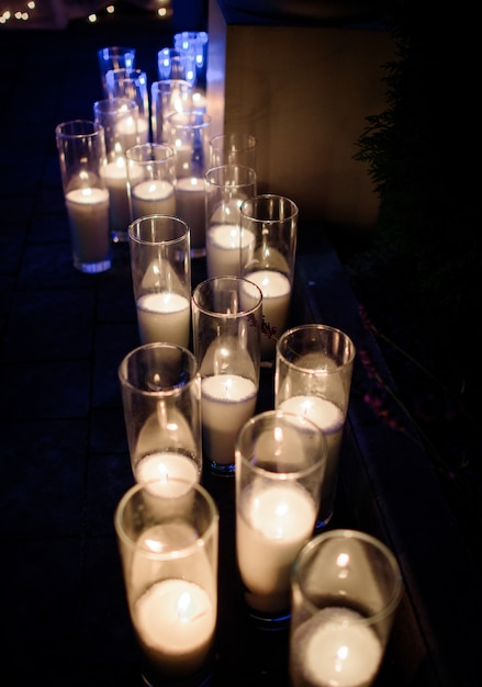 Free photo row of burning white candles in tall glass vases