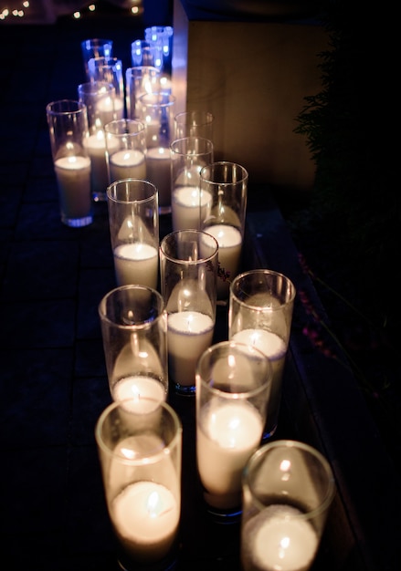 Row of burning white candles in tall glass vases