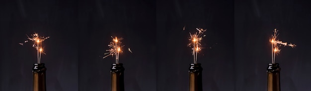 Row of champagne bottle with fire sparkler against black background