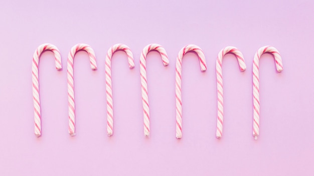Row of christmas peppermint cane candies on pink background