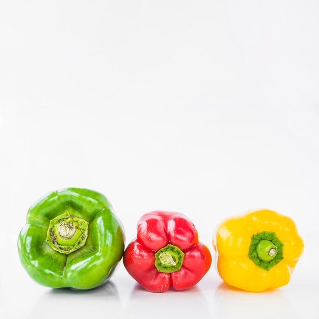 Row of colorful bell peppers on white surface