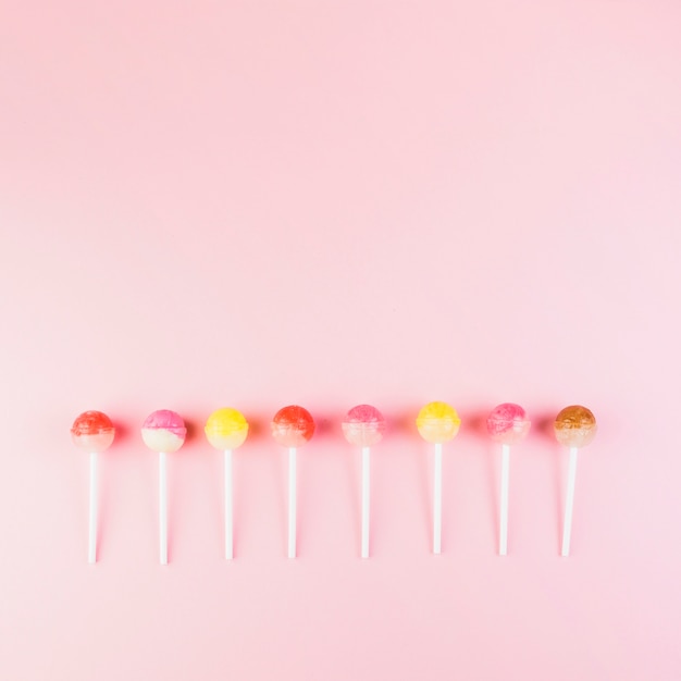 Row of colorful lollipops on pink background