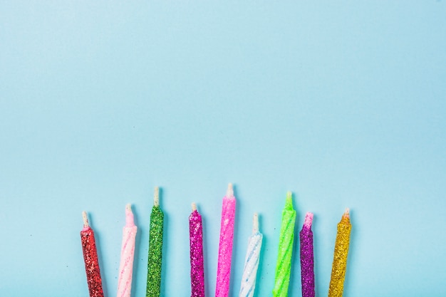 Row of colorful sparkling candles on blue backdrop