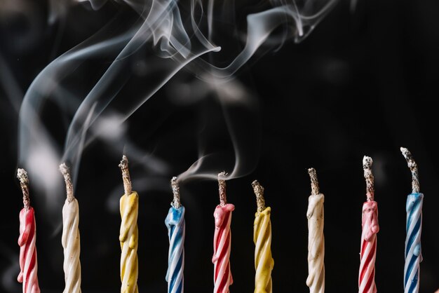 Row of extinguished candles arranged on black background