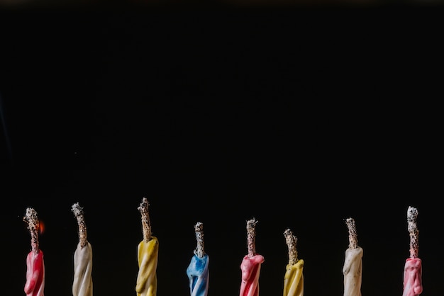 Row of extinguished candles arranged on black background