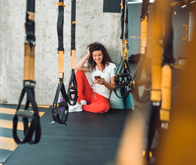 Row of fitness strap in front of woman listening to music on smartphone