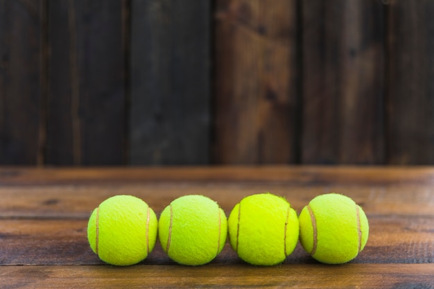 Foto gratuita fila di palline da tennis verde sul contesto strutturato in legno