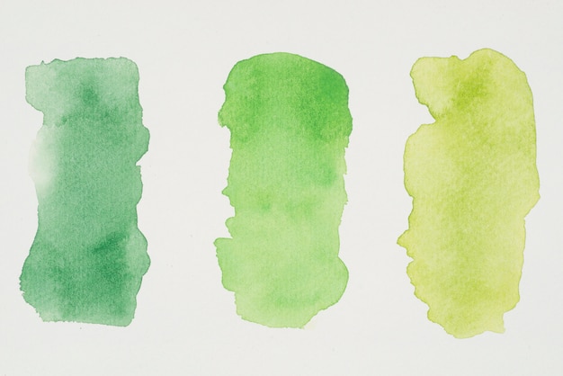 Row of green and yellow paints on white paper