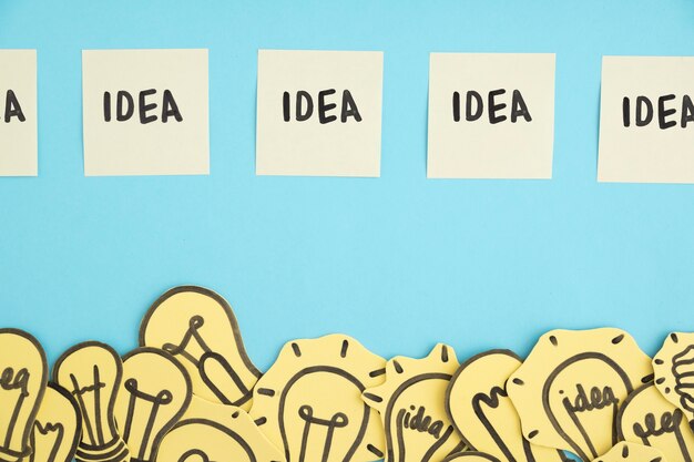 Row of idea adhesive notes over the border of many light bulbs against blue background