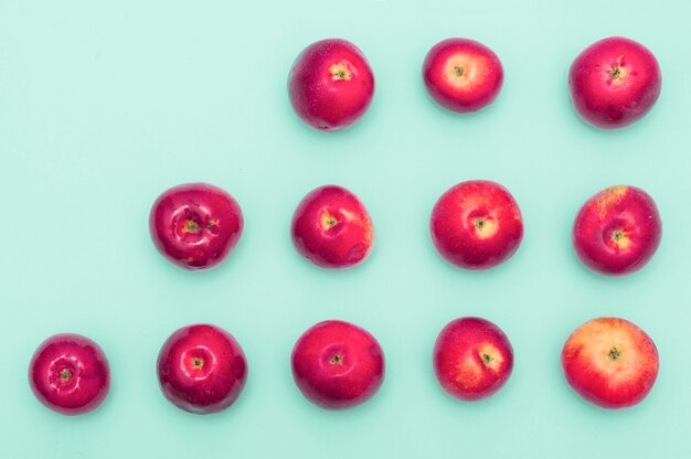 Row of increasing red apples against blue background