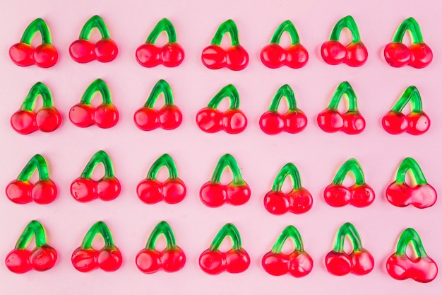 Row of jelly cherry candies on pink surface