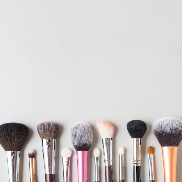 Row of makeup brushes at the bottom of white backdrop