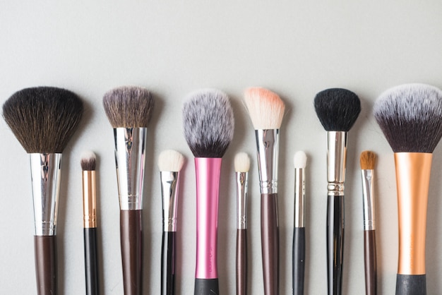 Row of makeup brushes on white surface