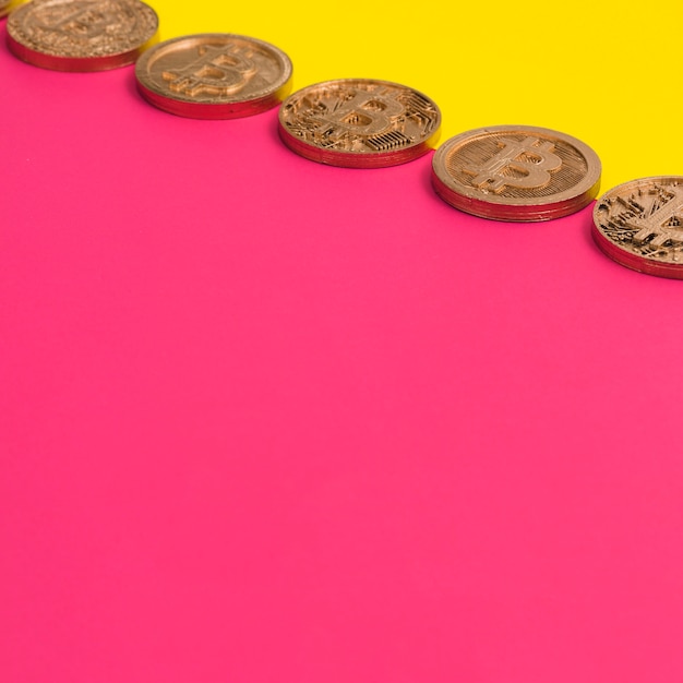 Row of many bitcoins over the yellow and pink dual background