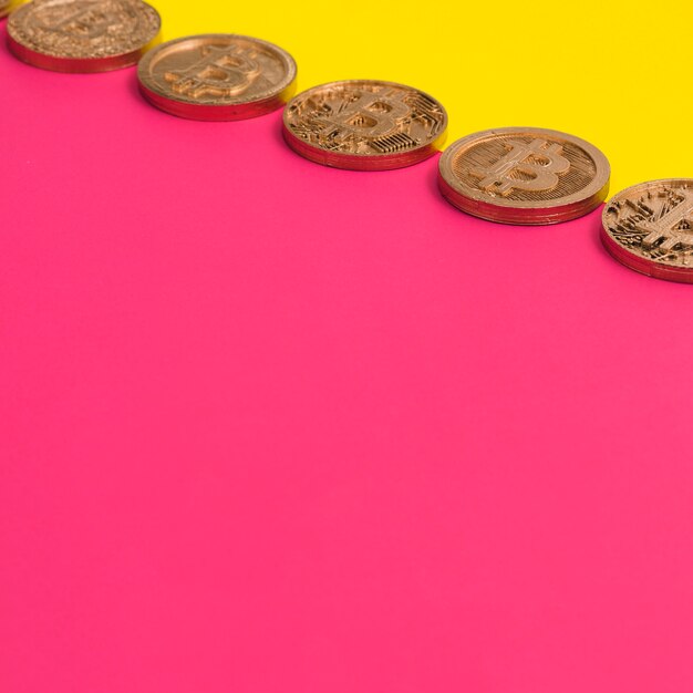 Row of many bitcoins over the yellow and pink dual background