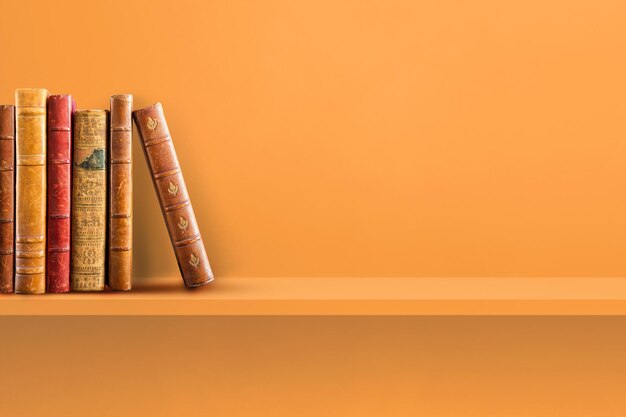 オレンジ色​の​棚​に​古い​本​の​列​。​水平​方向​の​背景​シーン