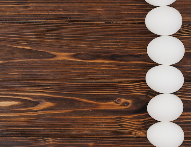 Бесплатное фото Ряд белых яиц на деревянный стол