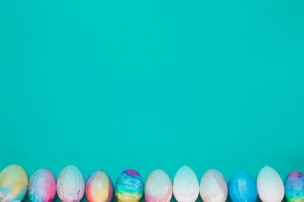 Row of painted easter eggs on the bottom of turquoise background
