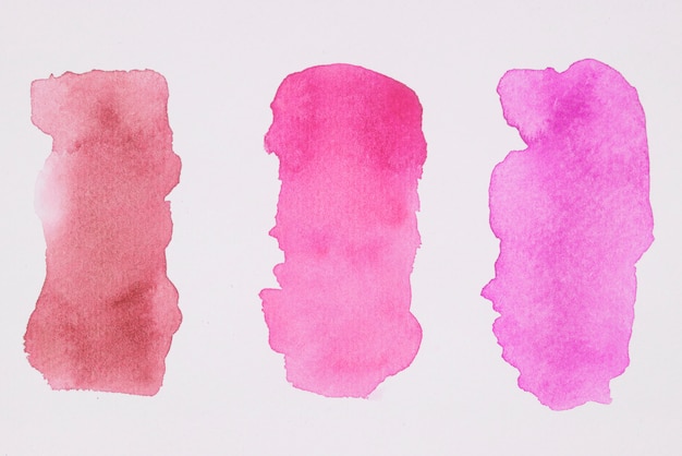 Row of pink and red paints on white paper