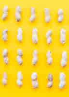 Foto gratuita fila di arachidi crude su sfondo giallo
