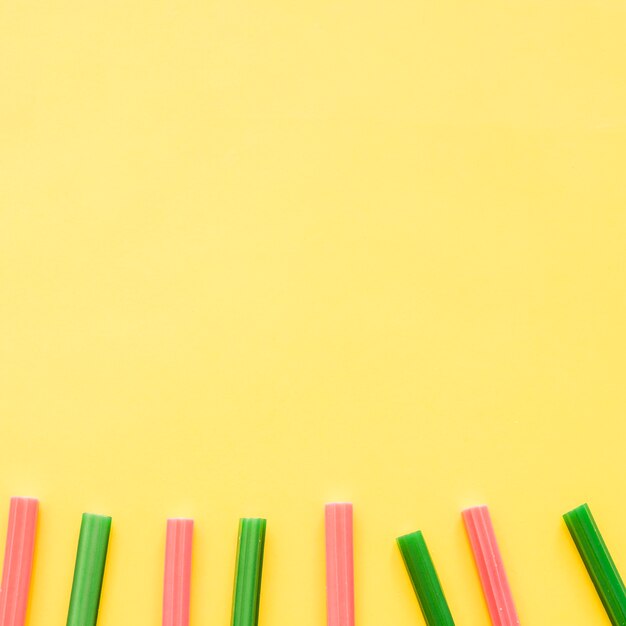 Row of red and green licorice candies on yellow background