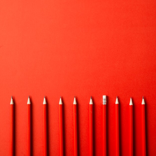 Row of red sharp pencils on red background