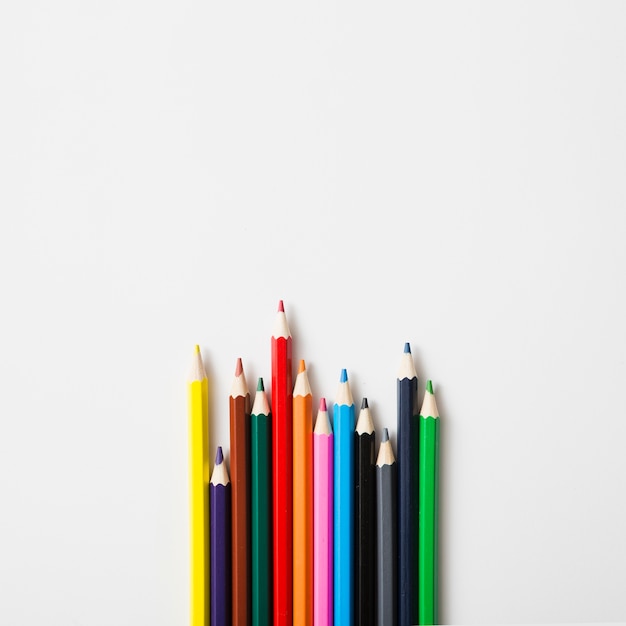 Ряд острых цветных карандашей на белом фоне
