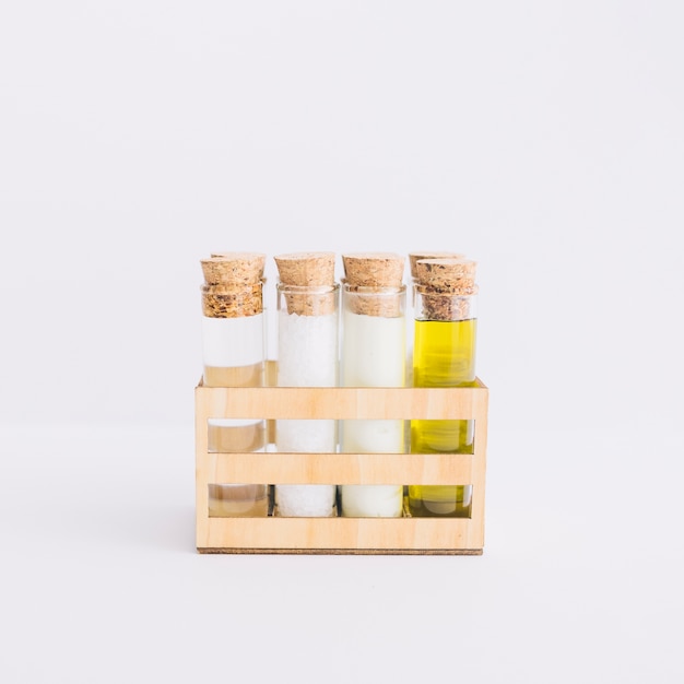 Row of test tubes with spa products in wooden container on white background