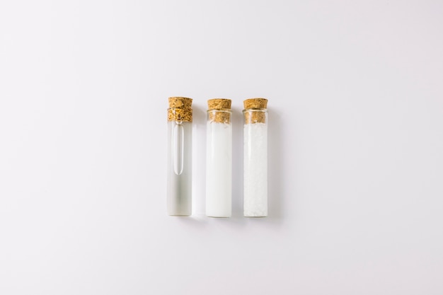 Row of three essential oils in test tubes on white backdrop