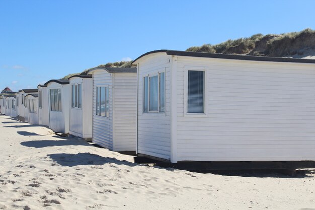 Ряд белых домиков на пляже Локкен, Дания