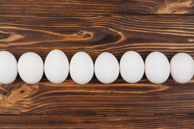 Ряд белых куриных яиц на деревянный стол