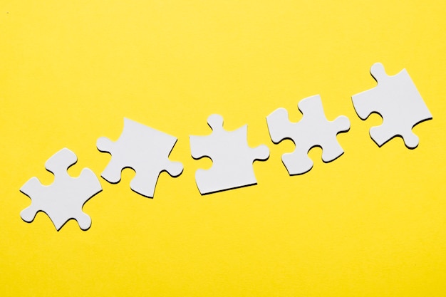 Row of white puzzle piece on yellow surface