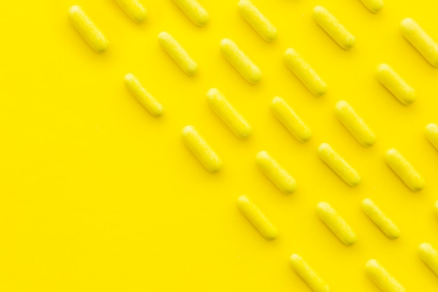 Free photo rows of candy capsules on yellow backdrop