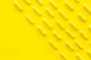 Free photo rows of candy capsules on yellow backdrop