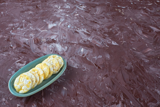 Rows of cheese chips on a plate , on the marble table.