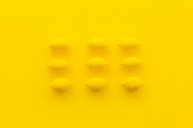 Rows of lemon candies on yellow background