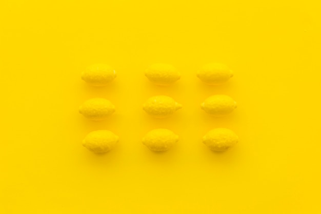 Rows of lemon candies on yellow background