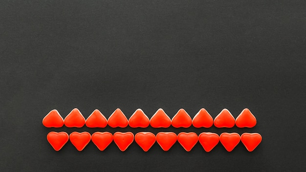 Free photo rows of red heart shape candies on black background