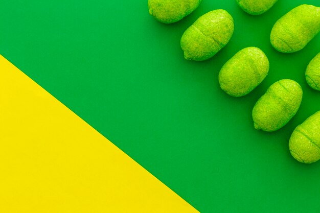 Rows of sweet candies on dual green and yellow backdrop