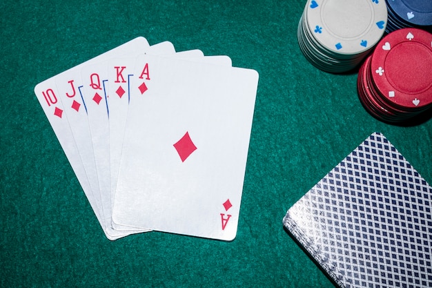 Royal flush playing cards with casino chips on poker table