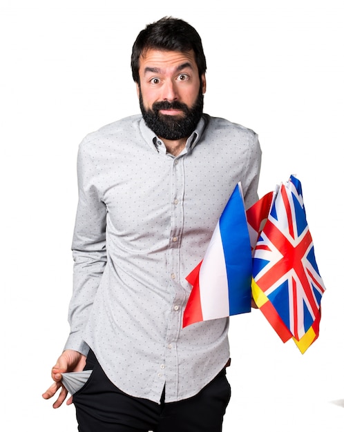 Ruined handsome man with beard holding many flags and looking money in their pockets