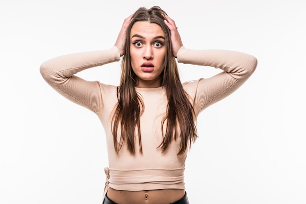 Ruined young woman in bright t-shirt holds arms on her head isolated on white