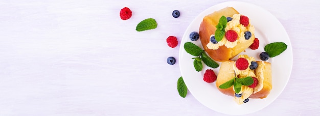 Rum savarian buns decorated with whipped cream and fresh berries