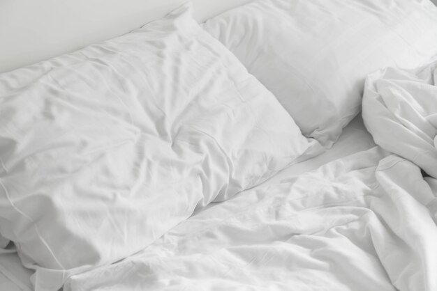 침실에 흰색 지저분한 베개 장식으로 구겨진 된 침대