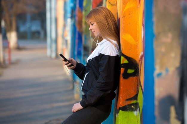 ストリートで携帯電話で休んでいるランナーの女の子