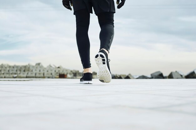 Runner man's feet running on road closeup on shoe